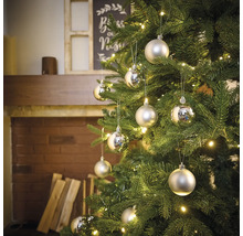 Ozdobený vianočný stromček so striebornými guľami a osvetlením v obývacej izbe