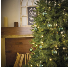 Ozdobený vianočný stromček s osvetlením a guľami vedľa krbu