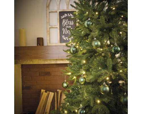 Ozdobený vianočný stromček s osvetlením a guľami vedľa krbu