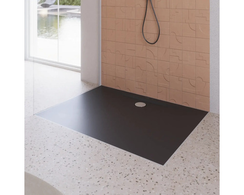 Čierna sprchová vanička v kúpeľni s obkladanou stenou a sprchou.