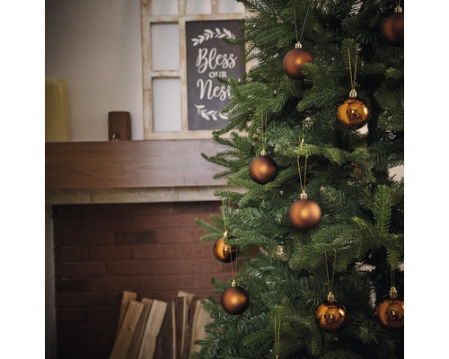 Zdobený vianočný stromček s guľami pred krbom