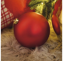 Dekoratívna červená vianočná ozdoba na chlpatom koberci