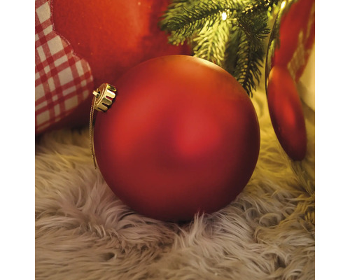 Dekoratívna červená vianočná ozdoba na chlpatom koberci