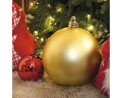 Veľká zlatá vianočná guľa pred vianočným stromčekom