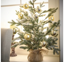 Dekoratívny zasnežený vianočný stromček so zlatými guľami v jutovom vreci