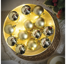 Zlaté vianočné gule so svetelnou reťazou na tanieri