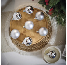 Dekoratívne vianočné gule v striebornej farbe na drevenom tanieri a stole