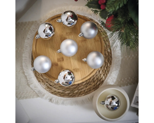 Dekoratívne vianočné gule v striebornej farbe na drevenom tanieri a stole