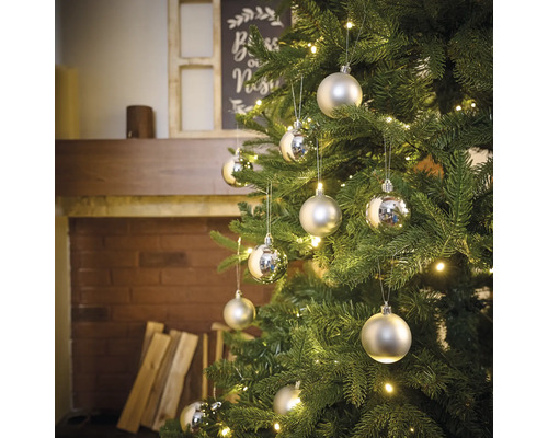 Ozdobený vianočný stromček s ozdobami a svetelnou reťazou pred krbom