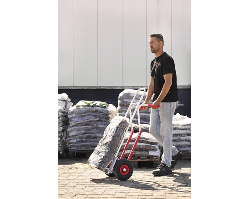 Muž prepráva vrecovaný tovar s rudlom pred skladom