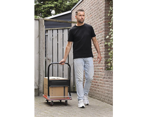 Muž ťahá rudlu s krabicami na dláždenej ceste