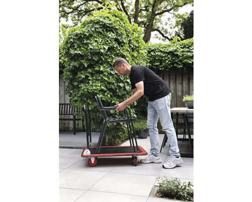 Muž prepravuje stoličky na rudli v záhrade