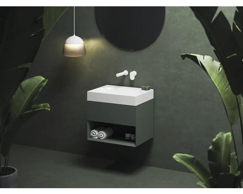 Moderná kúpeľňa s umývadlom, okrúhlym zrkadlom a tropickými rastlinami.