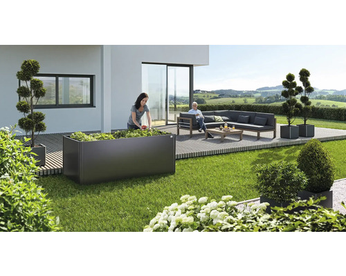 Záhradná scéna s vyvýšeným záhonom, ktorý sadí žena, a posedením s pohovkou a stolom