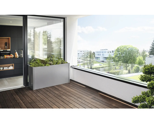 Scéna s osadeným obdĺžnikovým kvetináčom na balkóne s drevenou podlahou.