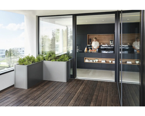 Balkón s kvetináčmi a otvorená kuchyňa so ženou, ktorá varí