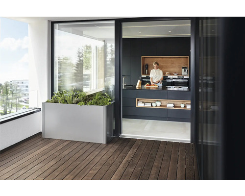 Balkónová scéna s kovovým kvetináčom a ženou v modernej kuchyni