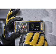 Logo spoločnosti DeWALT na digitálnom laserovom diaľkomere držanom pracovnými rukavicami