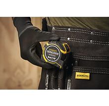 Zvinovací meter Stanley Fatmax v ruke s rukavicou a opaskom na náradie