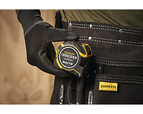 Zvinovací meter Stanley Fatmax v ruke s rukavicou a opaskom na náradie