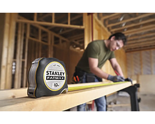 Zvinovací meter Stanley Fatmax vedľa remeselníka pracujúceho s drevom