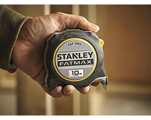 Zvinovací meter Stanley Fatmax s dĺžkou 10 metrov držaný v ruke.