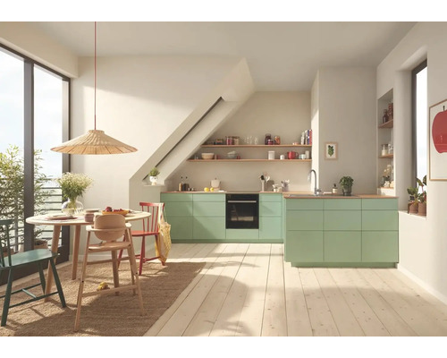 Svetlá kuchyňa s jedálenským kútom, vybavená zelenými kuchynskými skrinkami, dreveným stolom a stoličkami.