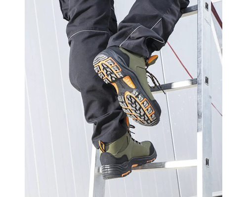Osoba stúpa po rebríku v zelených bezpečnostných topánkach.