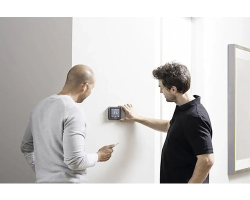 Dvaja muži inštalujú digitálny termostat na stenu