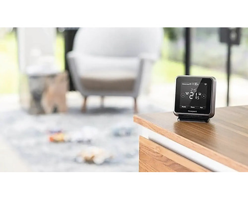 Inteligentný termostat Honeywell na drevenej skrini v obývacej izbe