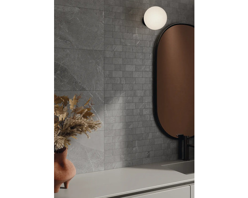 Kúpeľňa so sivými obkladmi stien v kamennom vzhľade, zrkadlom a lampou