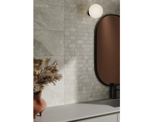 Nástenná dekorácia s obkladmi s kamenným vzhľadom a mozaikovými obkladmi, kombinovaná so zrkadlom a lampou