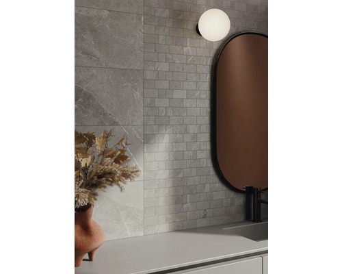 Kúpeľňa so sivými obkladovými dlaždicami so vzhľadom kameňa, zrkadlom a lampou