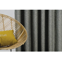 Dekoratívne závesy a ratanové kreslo s vankúšom v obývacej izbe