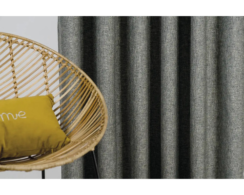 Dekoratívne závesy a ratanové kreslo s vankúšom v obývacej izbe