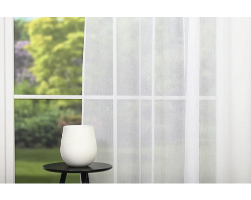 Okno s bielym závesom a váza na príručnom stolíku