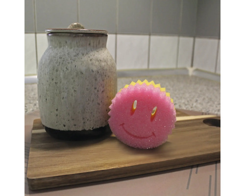 Keramická dóza s vekom a umývacia špongia s tvárou smajlíka na drevenej doske