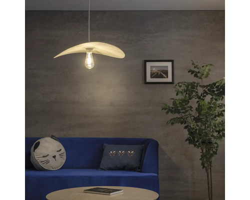 Obývacia izba s visiacou lampou, pohovkou a izbovou rastlinou.