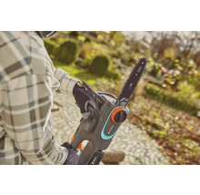 Osoba obsluhuje akumulátorovú reťazovú pílu Gardena v záhrade.