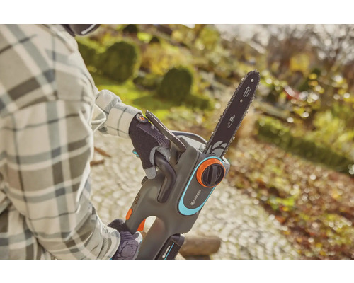 Osoba obsluhuje akumulátorovú reťazovú pílu Gardena v záhrade.