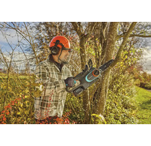 Muž s ochrannou prilbou a akumulátorovou pílou Gardena prerezáva strom.