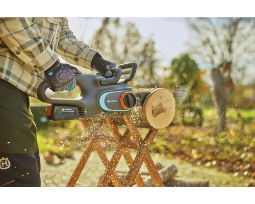 Akumulátorová reťazová píla v akcii pri rezaní klady na kozlíku