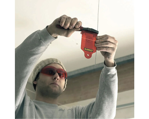 Osoba používa olovnicu na určenie zvislej línie.