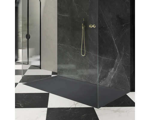 Sprchovací kút so sprchovacou vaničkou, sprchovacou armatúrou a sprchovacou zástenou pred čiernou mramorovou stenou