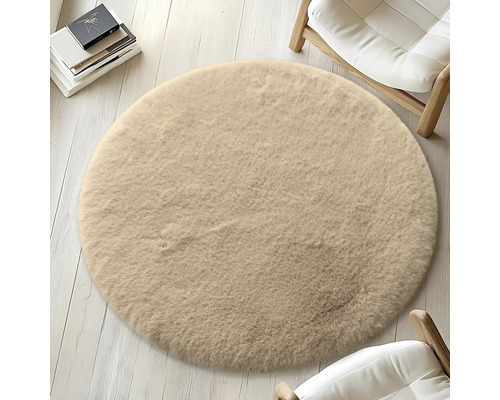 Okrúhly béžový koberec na svetlej drevenej podlahe, obklopený stoličkami a knihami.