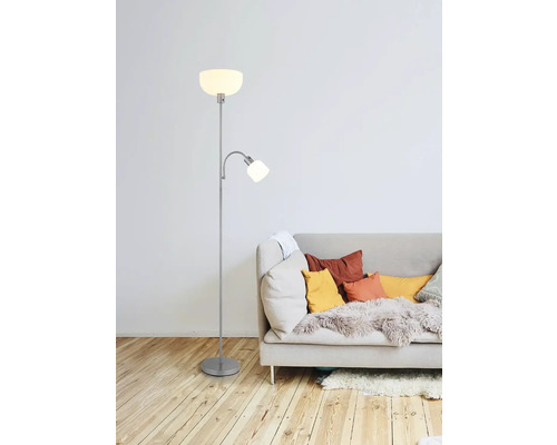 Stojaca lampa s lampou na čítanie vedľa pohovky s vankúšmi