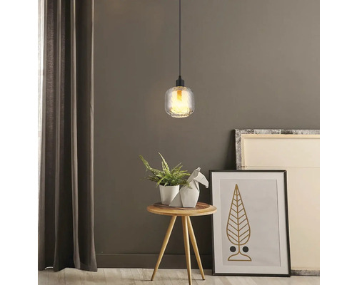 Závesná lampa nad odkladacím stolíkom s dekoráciou a obrazmi