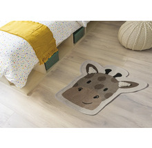 Izbová scéna s posteľou, sedákom a kobercom v tvare hlavy žirafy.