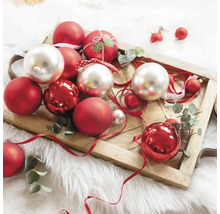 Ozdobné vianočné gule v červenej a striebornej farbe na drevenom podnose.