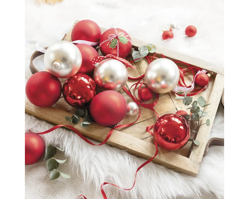 Ozdobné vianočné gule v červenej a striebornej farbe na drevenom podnose.